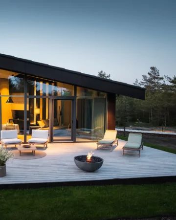 Modern outdoor living space with the contemporary Mix 850 fire pit creating warmth and atmosphere on a patio beside a glass-walled home